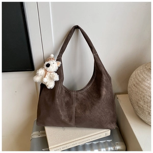 Detailed view of dark brown suede Hobo bag with white contrast stitching and bear charm