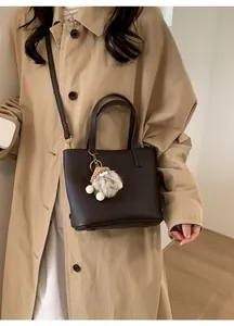 Dark brown lychee pattern leather handbag with plush doll charm and crossbody strap