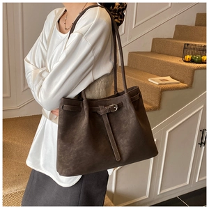 Detail of dark brown faux suede tote bag featuring silver buckles and drawstring texture