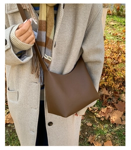 Close-up of brown pebbled leather texture and reinforced stitching on a bucket bag