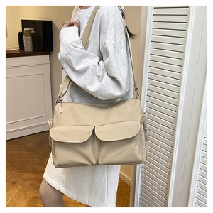 Detail of beige nylon crossbody bag featuring double pockets and adjustable wide strap