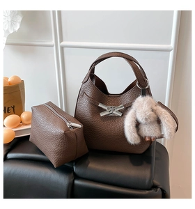 Detail of brown litchi pattern leather bucket bag with silver lock and plush bunny charm