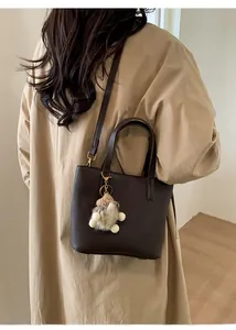 Detail of dark brown lychee grain leather crossbody bag styled with a beige coat