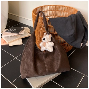 Detail of brown suede tote bag with white contrast stitching and plush bear charm