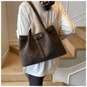 Detailed view of deep brown suede tote bag with decorative buckle strap and long shoulder strap