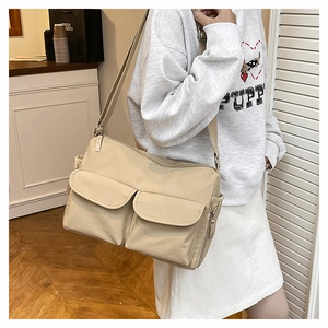 Detailed view of beige nylon crossbody bag with double front pockets on model