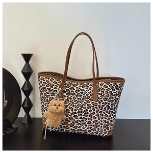 Detail view of large leopard print tote bag with a cute plush bear charm accessory