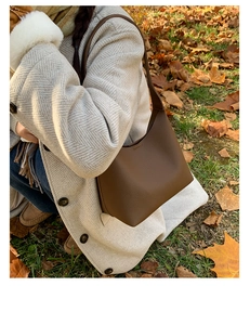Detail of dark brown pebble leather shoulder bag styled with beige autumn coat