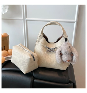 Detail of off-white lychee texture leather bucket bag with silver hardware and rabbit charm