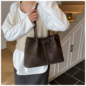 Detail of dark brown tote bag in matte suede texture with decorative leather buckle