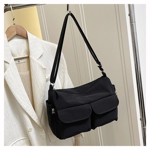 Detail of multi-pocket nylon crossbody bag showing matte texture and functional pockets