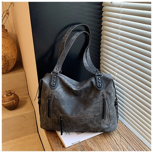 Détail d'un grand sac fourre-tout gris vintage avec fermetures éclair et pompons décoratifs