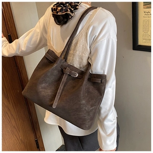 Detail of dark brown tote bag showing silver buckle and vintage PU leather texture