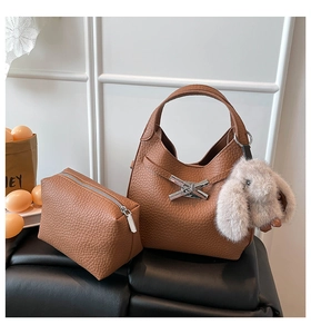 Close-up of brown textured bucket bag set with silver buckle and plush rabbit charm