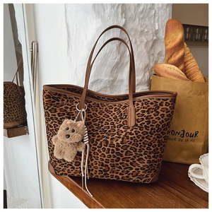 Macro shot of large leopard print tote bag with brown trim and small plush bear charm