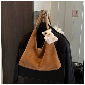 Close-up of brown suede tote bag featuring a cute white alpaca plush charm accessory