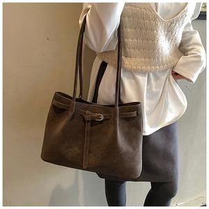 Close-up of a large coffee-brown suede tote bag with leather strap and metal buckle detail