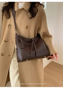 Gros plan sur un sac à main en cuir marron foncé avec détails de glands et pieds en métal