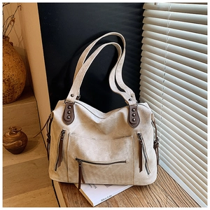 Détail du sac cabas en toile avec poignées en cuir marron et rivets sous lumière naturelle