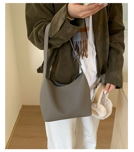 Minimalist grey pebbled leather bucket bag styled on shoulder with a stylish winter outfit