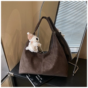 Detail of coffee brown faux suede tote bag with white contrast stitching and plush charm