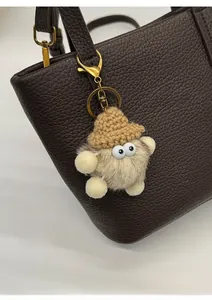 Detail of creative plush star pendant with knit hat on a brown leather tote bag
