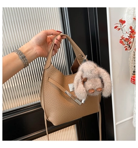 Close-up of brown litchi pattern leather bucket bag with cute plush bunny charm