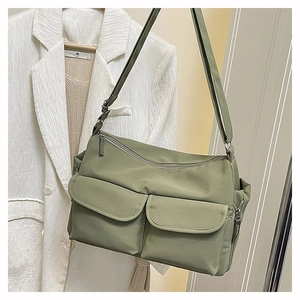 Detail of sage green nylon crossbody bag with dual cargo pockets and adjustable strap