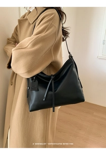 Détail du sac cabas minimaliste noir avec nœud sur un fond de manteau camel chic