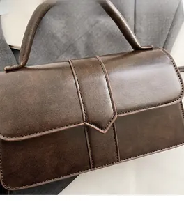 Close-up of vintage dark brown leather handbag showing clear texture and premium stitching