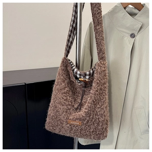 Detailed view of brown plush tote bag with wooden toggle button and plaid lining