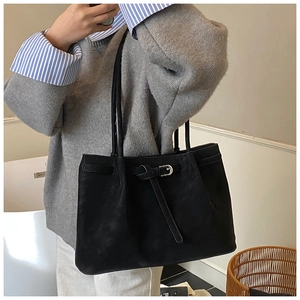 Detail of black matte leather tote bag with metal buckle and slim shoulder straps