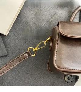 Detail of high-gloss gold hardware and dark brown vintage leather on the shoulder bag