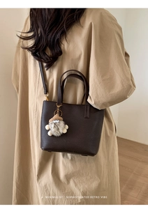 Detail of dark brown leather bucket bag with top handles and luxury pebble grain texture
