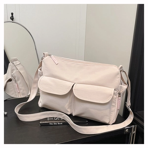 Close-up of beige nylon crossbody bag with dual front pockets and wide strap