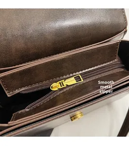 Detail of dark brown leather bag showing golden metal zipper and multiple compartments