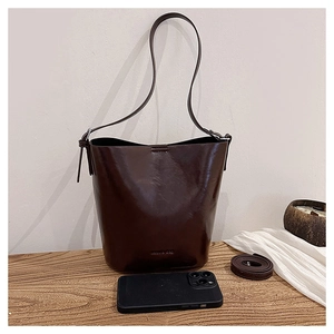 Detail of a dark brown vintage bucket bag with a logo and smartphone for size reference