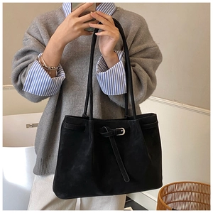 Close-up of large black tote bag featuring matte suede texture and silver buckle detail