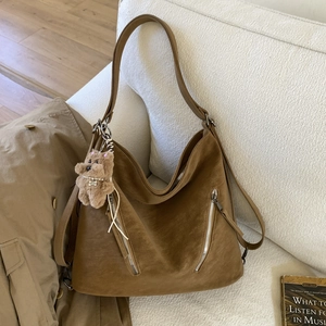 Macro shot of retro brown suede tote bag details with metal zippers and cute teddy charm