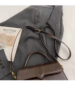 Detail view of adjustable shoulder strap and gold buckle on a retro brown bag