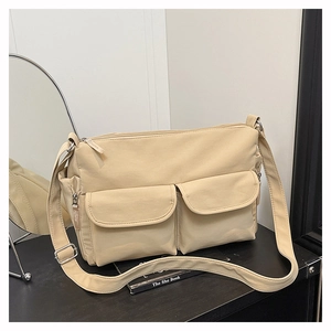 Detail of beige nylon crossbody bag featuring double front flap pockets and wide strap