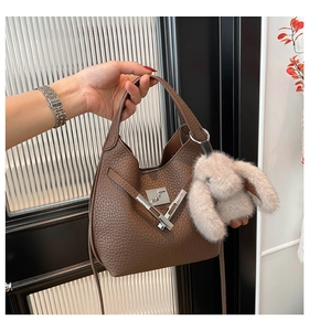 Brown litchi leather bucket bag with silver hardware and a plush rabbit charm