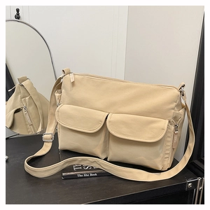Detailed close-up of beige nylon crossbody bag with dual front pockets and silver zipper
