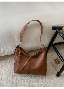 Détail d'un sac hobo en cuir marron avec noeud décoratif et étiquette de marque MUNETI