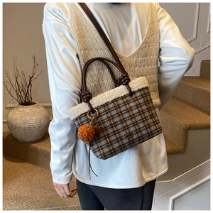 Détail du sac à carreaux avec bordure en peluche et accessoire pompon rouge moelleux
