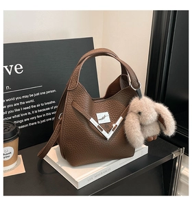 Close-up of vintage brown bucket bag with lychee texture and cute rabbit charm