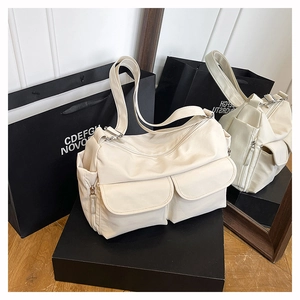 Detail view of the cream white nylon shoulder bag with functional flap pockets and silver hardware