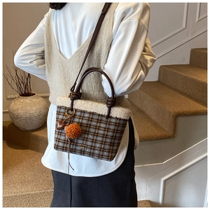 Détail du sac seau à carreaux en tweed avec bordure en laine, poignées et breloques