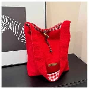 Detail of red wool felt tote bag featuring checkered lining and wooden toggle closure