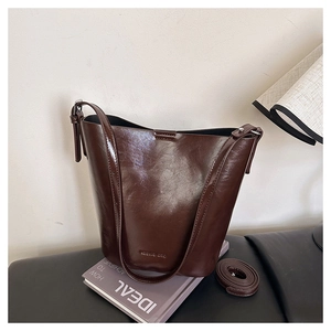 Detail of vintage dark brown leather bucket bag showing its glossy textured finish and strap